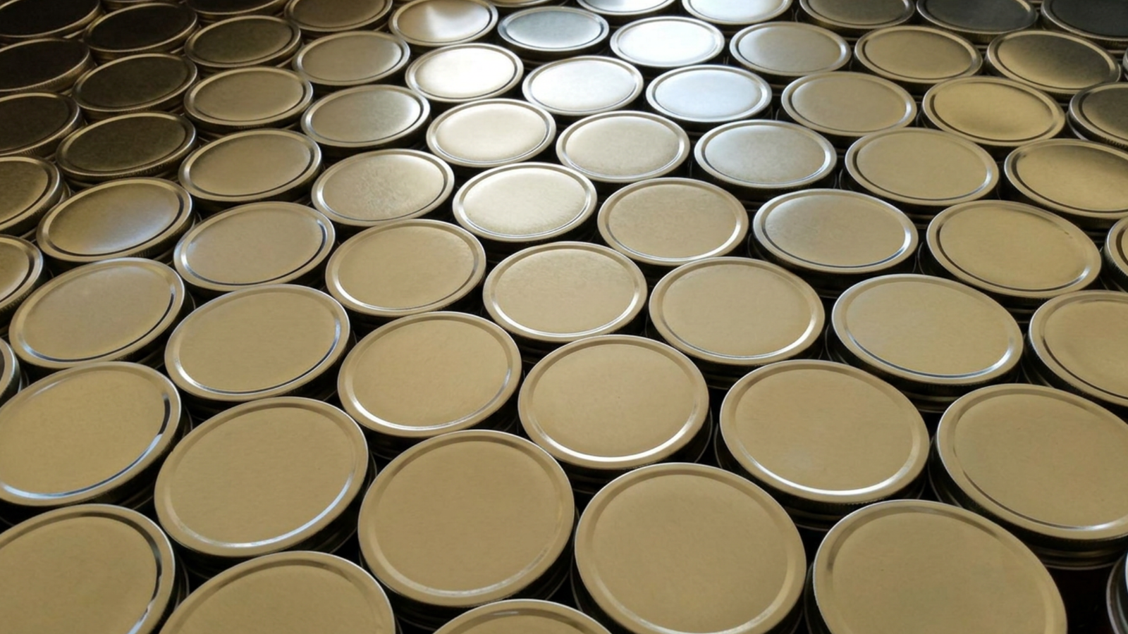 Rows of gold metal mason jar canning lids viewed from above.