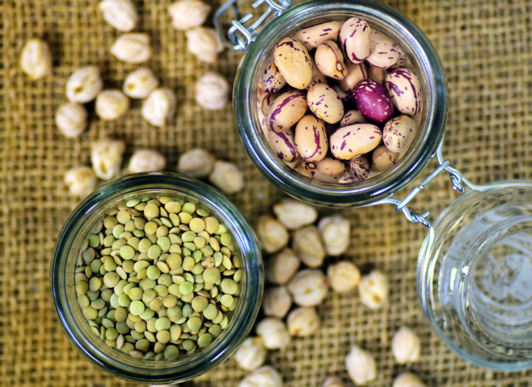 Dried beans and lentils stored in glass jars on burlap, decanted from their original bulk packaging