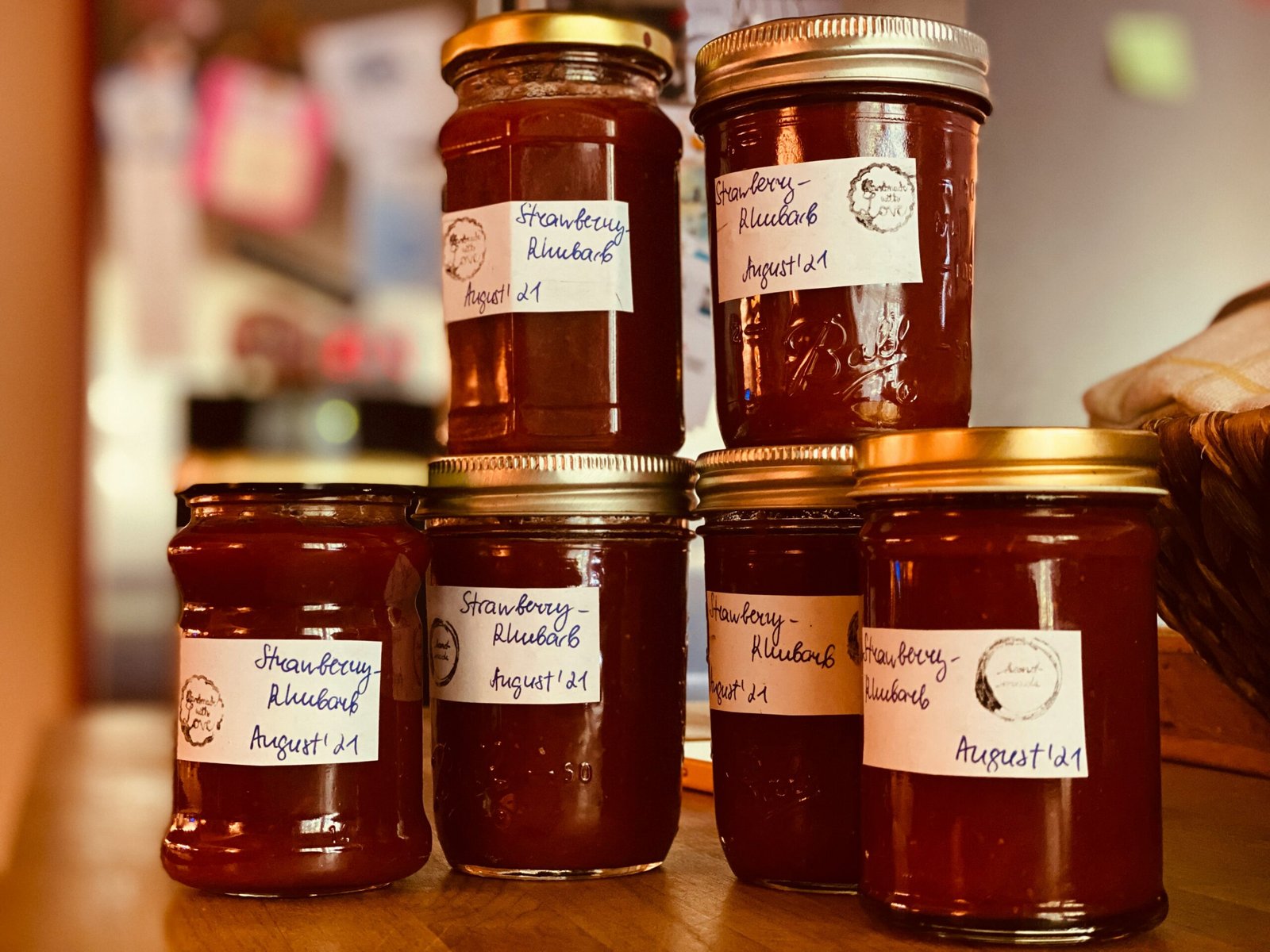 Stacked jars of homemade strawberry-rhubarb jam with handwritten labels dated August 2021